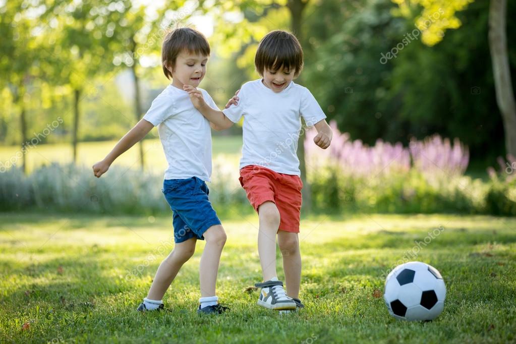 Two cute little kids, playing football together, summertime. Chi Stock