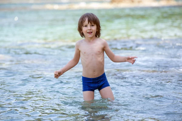 Süßes Porträt eines kleinen Jungen am Strand, der im Wasser spielt — Stockfoto