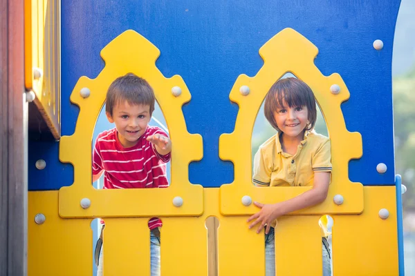Lindos niños, hermanos, miradas a través del agujero en el patio de recreo ou — Foto de Stock