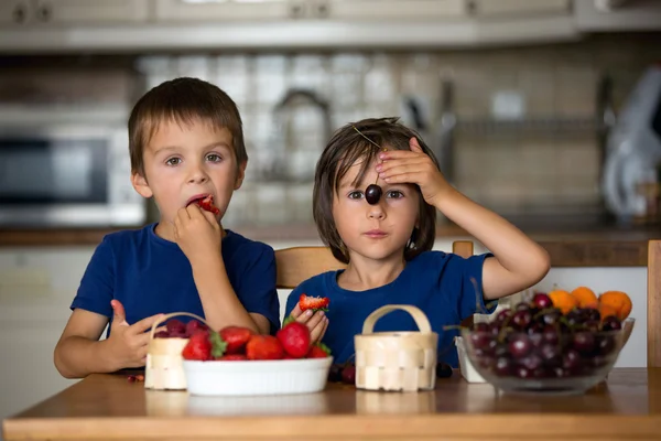 Duas crianças doces, irmãos meninos, comendo frutas frescas em casa — Fotografia de Stock