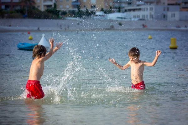 Dos niños dulces, salpicándose entre sí con agua en la playa — Foto de Stock