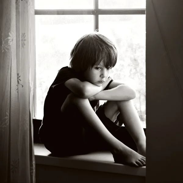 Smutne, dziecko, chłopiec, siedzi na tarczy okna — Zdjęcie stockowe
