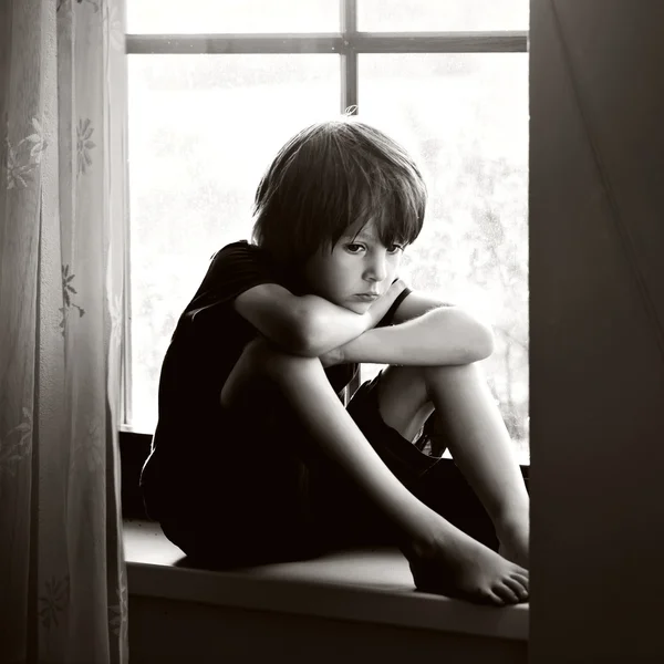 Niño triste, muchacho, sentado en un escudo de ventana — Foto de Stock