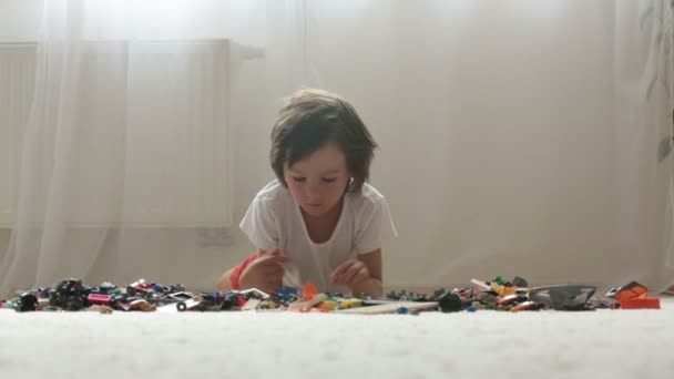 Söta lilla förskola barnet, pojke, spelar hemma med konstruktören block, bygga leksaker, söka efter dem med förstoringsglas — Stockvideo
