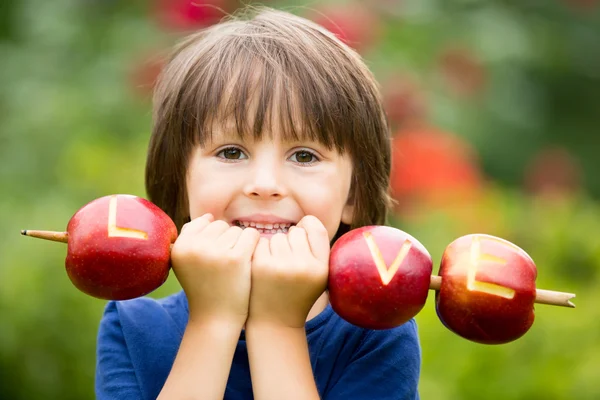 Carino bambino, ragazzo, tenendo un segno d'amore, fatto di mele, l — Foto Stock