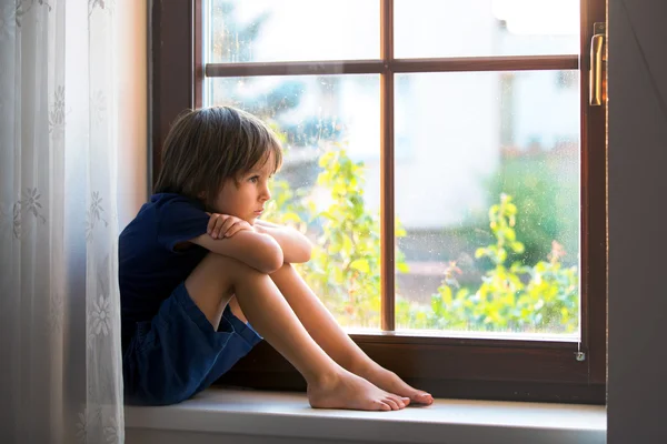 Trauriges Kind, Junge, auf einem Fensterschild sitzend — Stockfoto