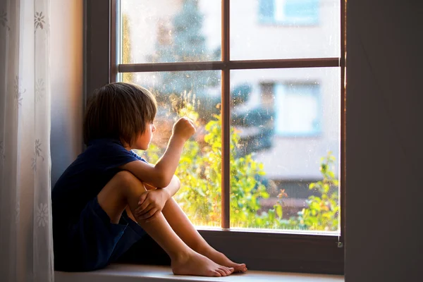 Triste enfant, garçon, assis sur un bouclier de fenêtre — Photo