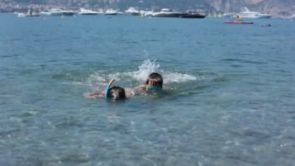 Dos chicos lindos con gafas de natación y snorkel nadando en el mar, riviera francés, aprendiendo a nadar — Vídeo de stock