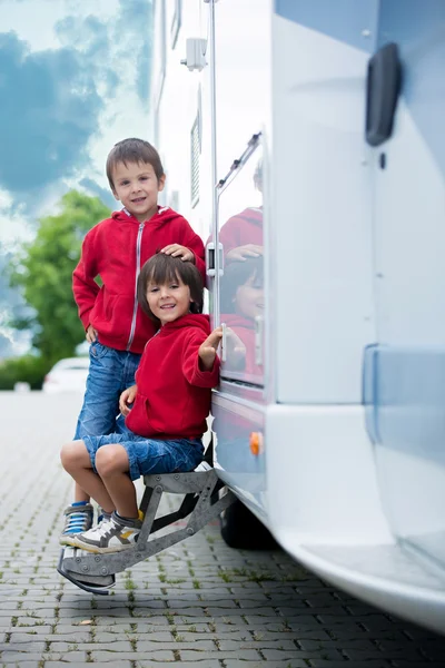 Miúdos giros, irmãos rapazes, sentados à porta de uma caravana — Fotografia de Stock