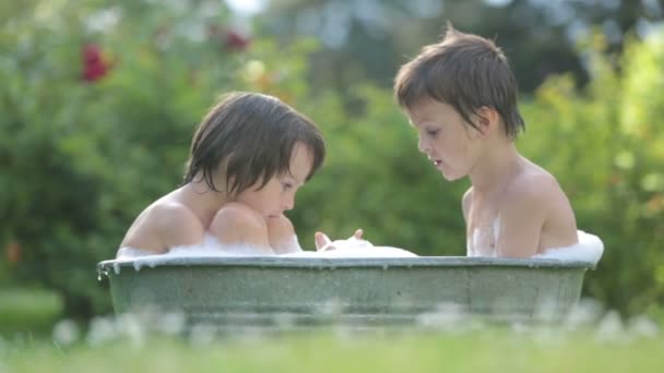 Duas crianças, irmãos meninos, tomando banho ao ar livre, fazendo bolhas de sabão, verão — Vídeo de Stock