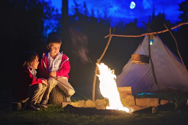 Zwei süße Jungs sitzen nach Sonnenuntergang am Lagerfeuer — Stockfoto