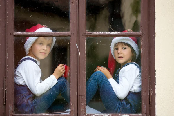 Zwei süße Jungen, Brüder, die durch ein Fenster schauen und auf sie warten — Stockfoto