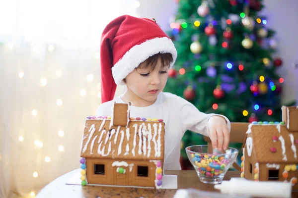 クリスマスのジンジャーブレッド クッキーの家を作る、かわいい男の子 — ストック写真