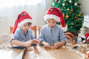 Two cute boys with santa hat, preparing cookies at home, Christm clipart