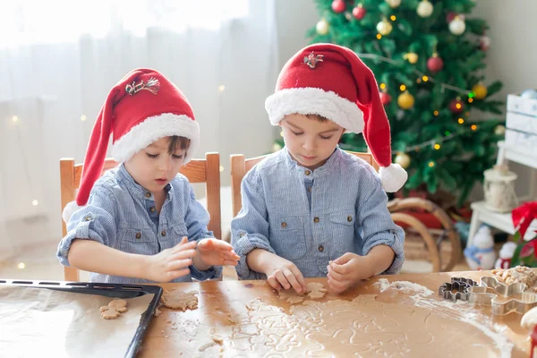 Twee Superleuke jongens met kerstmuts, voorbereiding van cookies thuis, kiest — Stockfoto