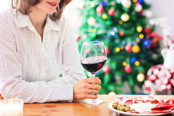 Mujer joven, bebiendo vino y merienda en casa en Navidad —  Fotos de Stock
