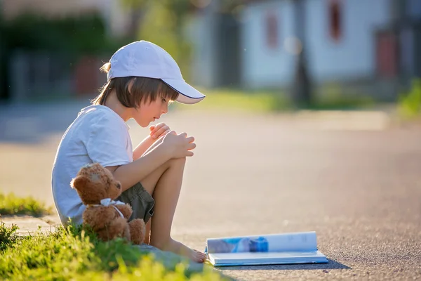 Vacker liten pojke, en bok på gatan, sittande wi — Stockfoto