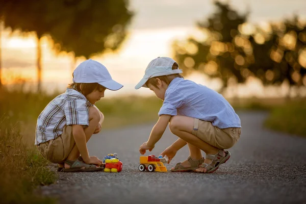 Két gyermek, fiú testvér, szabadban szórakozik játékszert autók — Stock Fotó