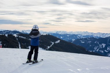 Çocuğum, güneşli bir günde kış kayak merkezinde kayak yapmak, manzaranın tadını çıkarmak