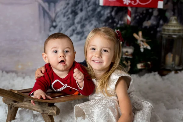 可爱的小男孩和带着圣诞装饰品的小女孩一起在雪地里玩耍 — 图库照片