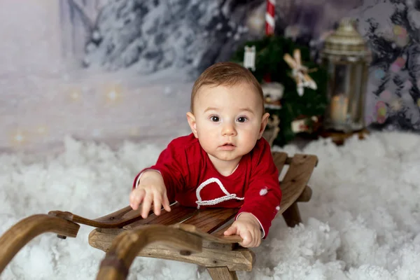 雪の中で遊んでクリスマスの飾りを持つ甘い小さな赤ちゃんの男の子 — ストック写真