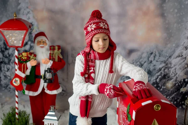 小孩子 用圣诞邮筒寄信给桑塔 给他周围的圣诞装饰 外面的雪景 — 图库照片