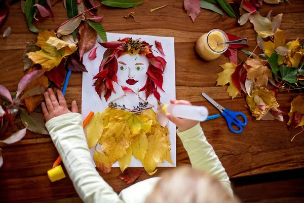 Toddler金发碧眼的孩子 在客厅里创作女性的树叶肖像 用胶水涂树叶 — 图库照片