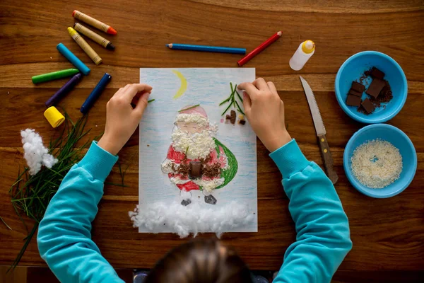 学校の子供 男の子 サンタクロースの写真を描き さまざまな要素で彼を飾る チョコレート ココナッツ — ストック写真