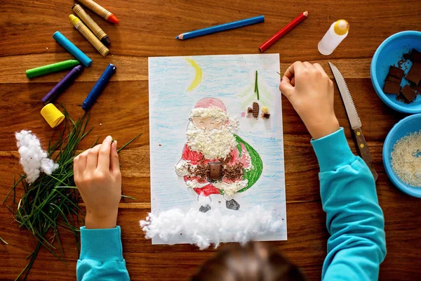 学校の子供 男の子 サンタクロースの写真を描き さまざまな要素で彼を飾る チョコレート ココナッツ — ストック写真