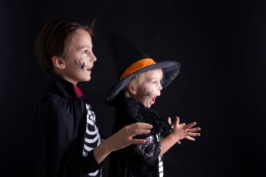 Cadılar Bayramı için giyinmiş, evde oynayan, siyah arka planda izole edilmiş bir çocuk.