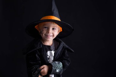 Cadılar Bayramı için giyinmiş, evde oynayan, siyah arka planda izole edilmiş bir çocuk.