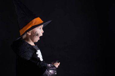 Cadılar Bayramı için giyinmiş, evde oynayan, siyah arka planda izole edilmiş bir çocuk.