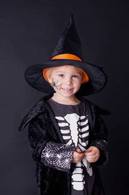 Cadılar Bayramı için giyinmiş, evde oynayan, siyah arka planda izole edilmiş bir çocuk.
