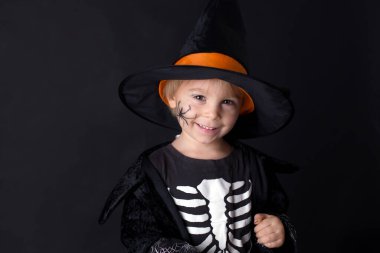 Cadılar Bayramı için giyinmiş, evde oynayan, siyah arka planda izole edilmiş bir çocuk.