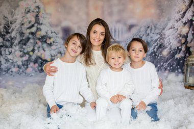 Anne ve üç çocuğu var, çocuklar, karda aile fotoğrafı için poz veriyorlar.