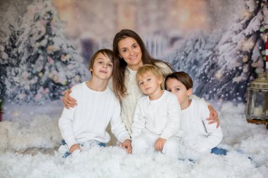 Anne ve üç çocuğu var, çocuklar, karda aile fotoğrafı için poz veriyorlar.