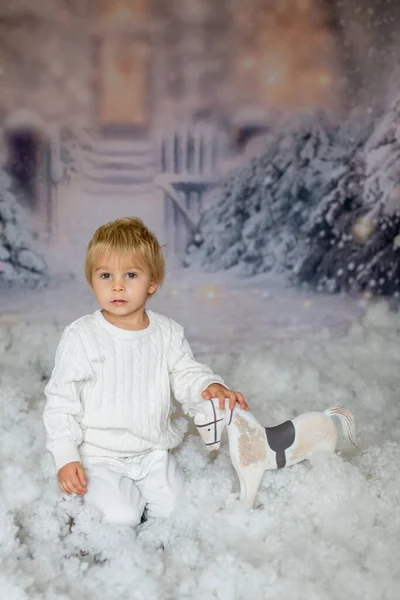 Netter Kleiner Blonder Junge Der Mit Weißem Holzpferd Schnee Spielt — Stockfoto