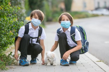 Okul çocukları, çocuklar, yaz tatilinden sonra okula geri dönmek, çocuklar Coronavirus COVID 19 yüzünden maske takarak okula gitmek.