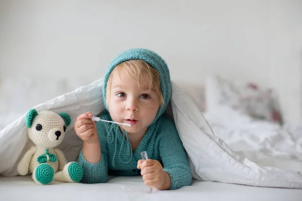 かわいいです幼児の男の子とともに手作りのニットおもちゃ ベッドに横たわっ — ストック写真