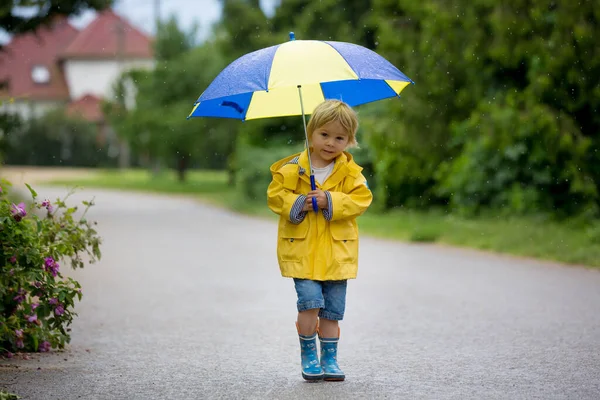 母親と幼児 男の子 雨の中で遊んで ブーツとレインコートを着て — ストック写真