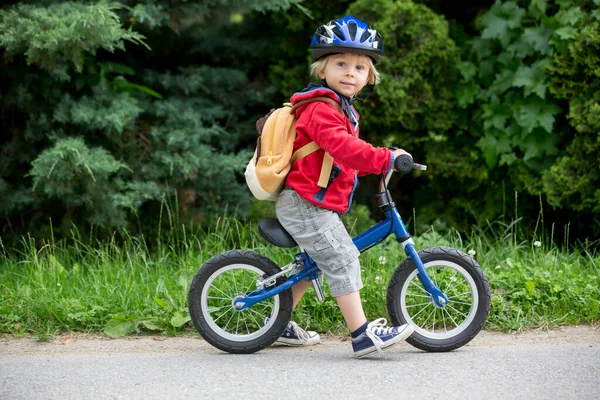 青いヘルメットとかわいい幼児の男の子 路上でバランス自転車に乗る 背景がぼやけて — ストック写真