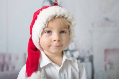 Kırmızı Noel Baba şapkalı güzel çocuk elinde süt, içki ve Noel süsüyle şişe tutuyor.