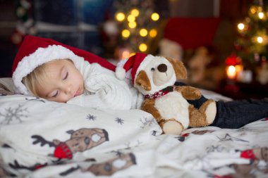 Tatlı sarışın çocuk, Noel 'de oyuncakla yatakta uyuyor.