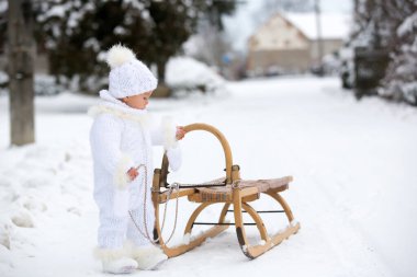 Tatlı küçük çocuk, kış günü dışarıda karla oynuyor, kar yağıyor.
