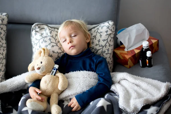 ブロンドの幼児の男の子 リビングルームのソファで寝て 発熱と横になって お母さんは彼をチェック — ストック写真