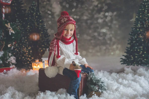 小さな幼児の子供スーツケースと小さなジンジャーおもちゃを手に 雪の森の中を歩く クリスマスのテーマ画像 — ストック写真