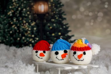 Karda kızağın üstünde renkli şapkaları olan el yapımı küçük bir kardan adam kafası.