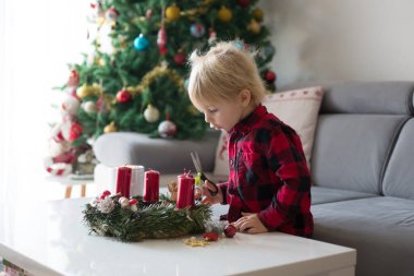 Küçük tatlı sarışın çocuk, evde çelenk yapıyor, dekore ediyor.