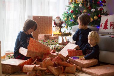 Mutlu çocuklar, çocuklar, Noel günü hediyeleri açıyorlar, pijama giyiyorlar.
