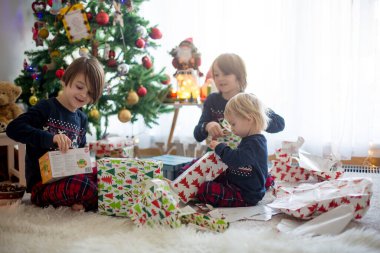 Mutlu çocuklar, çocuklar, Noel günü hediyeleri açıyorlar, pijama giyiyorlar.